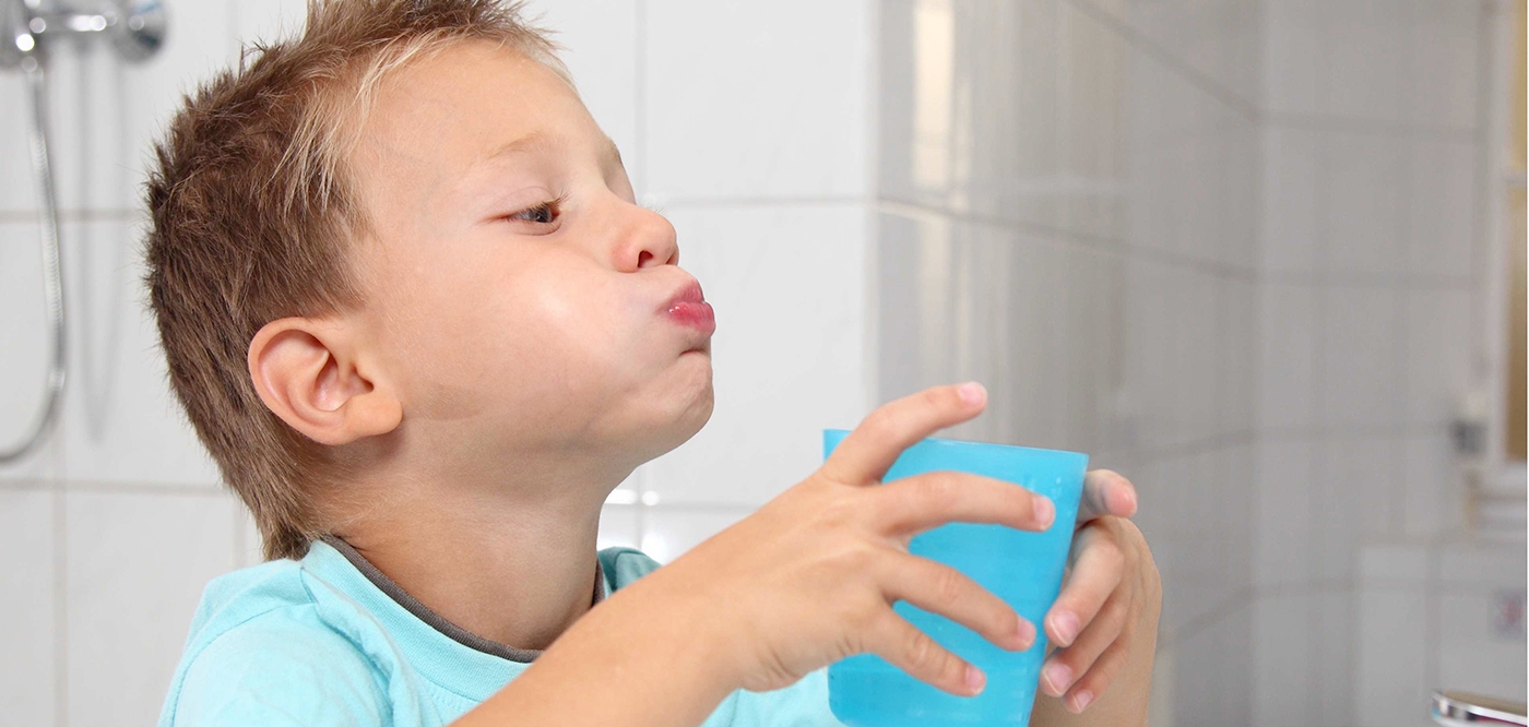 child washing mouth after brushing teeth
